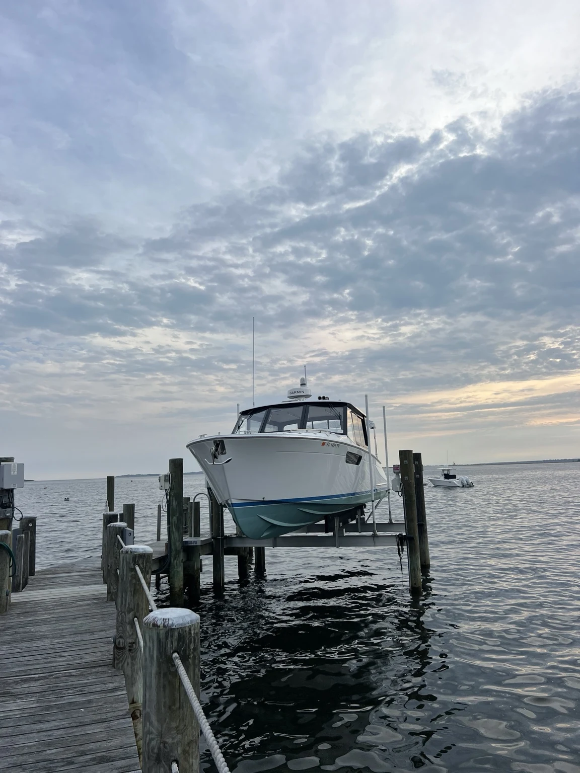 Finished boat on a waterfront lift beneath an evening sky